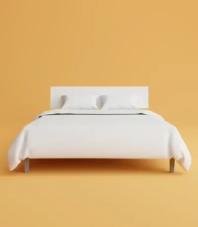 a bed with a white cover and pillows on top of it